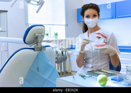 Dentista donna in maschera in stomatologia office azienda dental modello di ganascia. Health care concept Foto Stock