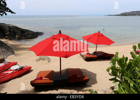 Rosso brillante ombrelloni su una spiaggia esotica giornata di sole Foto Stock
