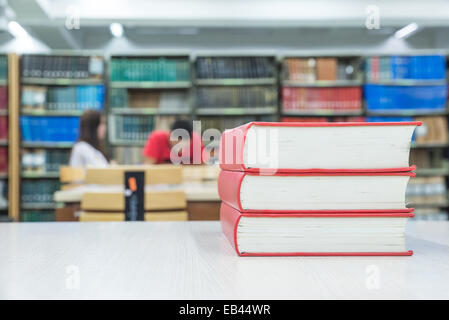 Una pila di libri con la biblioteca sul retro Foto Stock
