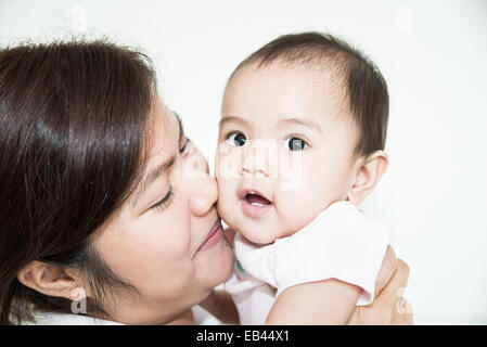 Felice famiglia allegra. Asian il bambino e la madre baciare, ridendo e abbracciando Foto Stock