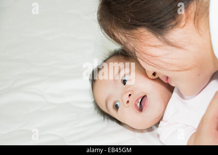 Felice famiglia allegra. Asian il bambino e la madre baciare, ridendo e abbracciando Foto Stock