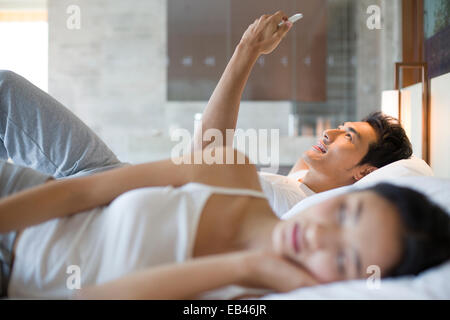 Giovane uomo utilizzando smart phone sul letto Foto Stock