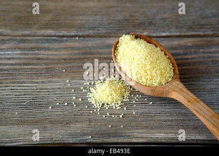 Couscous crudo in un cucchiaio di legno su schede, cibo close up Foto Stock