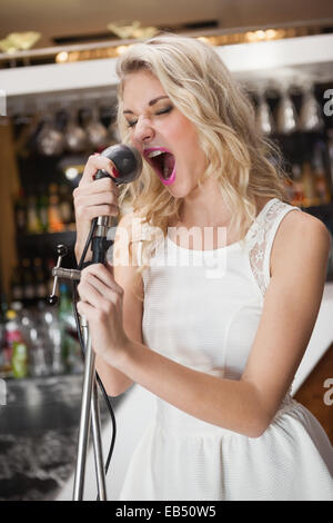 Giovane e bella donna cantare in un microfono Foto Stock