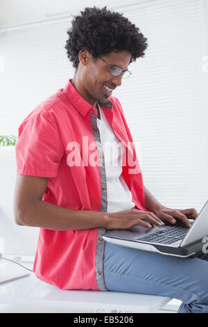 Imprenditore seduto sulla sua scrivania con computer portatile Foto Stock