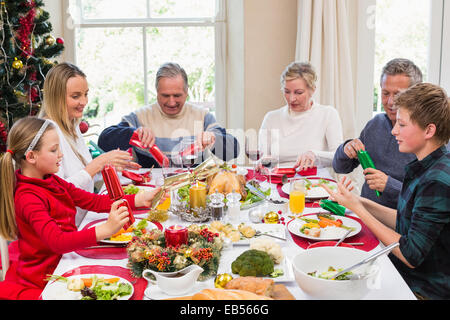 Famiglia tirando Christmas Cracker al tavolo da pranzo Foto Stock