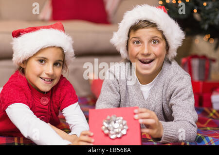 Sorpreso il fratello e a santa hat sorella apre un regalo Foto Stock
