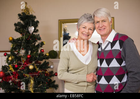 Coppia senior sorridente accanto al loro albero di natale Foto Stock