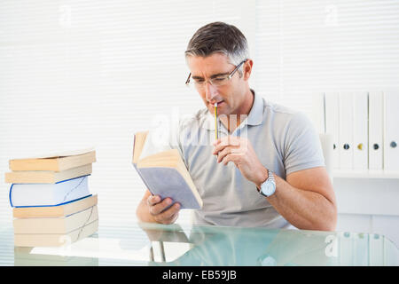 Uomo con occhiali il pensiero e la lettura di un libro Foto Stock
