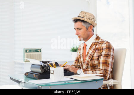 Retrò uomo nel cappello di paglia digitando su una macchina da scrivere Foto Stock