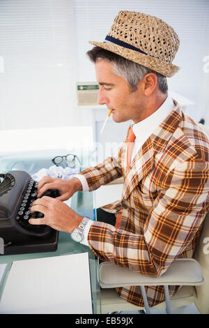 Vintage uomo nel cappello di paglia digitando su una macchina da scrivere Foto Stock