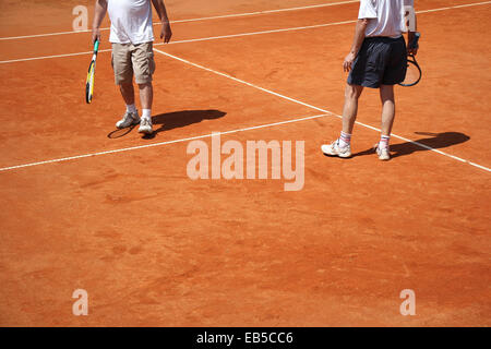 Voce maschile giovane giocando a tennis presso la corte in una giornata di sole Foto Stock