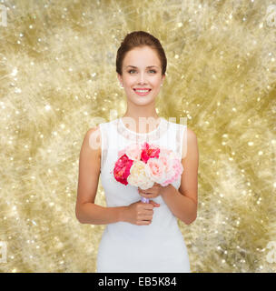 Donna sorridente in abito bianco con bouquet di rose Foto Stock