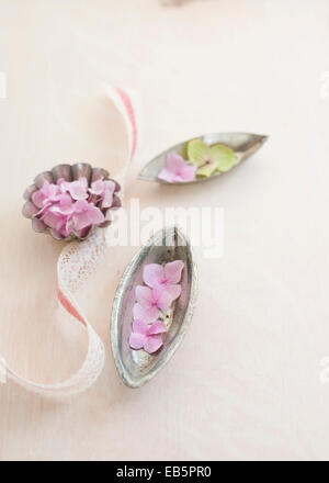 Vintage tre teglie con i fiori delle ortensie in distressed shabby chic avorio dipinta sullo sfondo di legno e rosa lacy ribbon Foto Stock