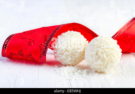 Snowball di cocco tartufi su sfondo bianco. Disposizione dei cookie di noce di cocco in legno elegante sfondo. Foto Stock