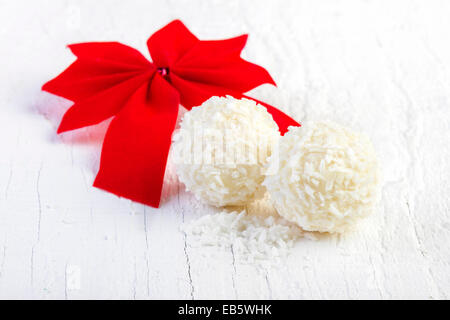 Snowball di cocco tartufi su sfondo bianco. Disposizione dei cookie di noce di cocco in legno elegante sfondo. Foto Stock