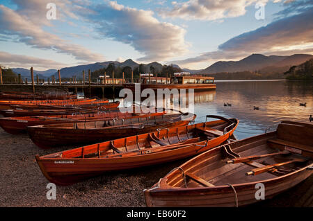 Barche a remi e il lancio di Derwent, ormeggiata come il sole tramonta su Derwent Water nella periferia di Keswick Foto Stock
