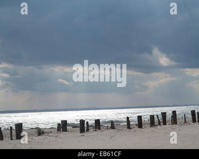 Oceano atlantico shore linea con dock in legno light blue sky rottura sole gettò le nuvole rendendo la riflessione di argento sul mare Foto Stock