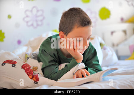 Ragazzo giovane per leggere un libro nel letto nella mattina tempo Foto Stock