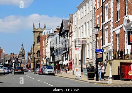 Edifici e negozi lungo Bridge Street con San Pietro e la chiesa di St Michaels chiesa alla parte posteriore di Chester, Cheshire, Inghilterra, Regno Unito Foto Stock
