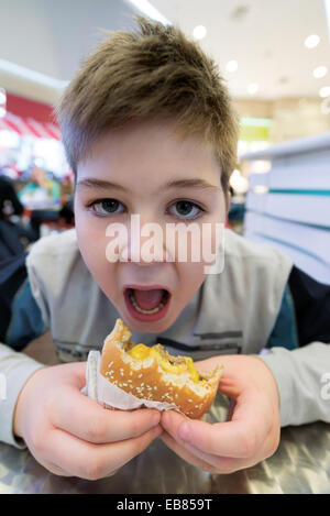 Teen boy mangia hamburger n Cafe Foto Stock