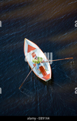 Vista aerea di un anziano che voga una piccola barca a remi in vetroresina / skiff / dinghy, Finlandia Foto Stock