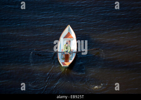 Vista aerea di un uomo anziano che rema una piccola barca in vetroresina / skiff / dinghy , Finlandia Foto Stock