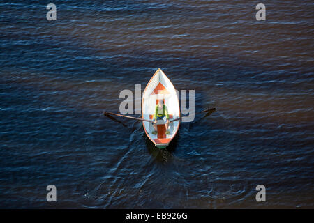 Vista aerea di un uomo anziano che rema una piccola barca in vetroresina / skiff / dinghy , Finlandia Foto Stock