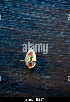 Vista aerea di un anziano che rema una piccola barca a remi in vetroresina / skiff / dinghy , Finlandia Foto Stock