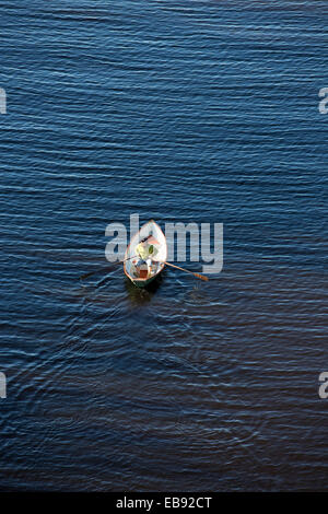 Vista aerea di un anziano che rema una piccola barca a remi in vetroresina / skiff / dinghy , Finlandia Foto Stock