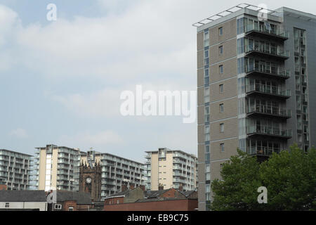 Sunny View, dal fiume Irwell marciapiede, torre alta sopra i blocchi di case in mattoni e la sacra Chiesa della Trinità, Salford, Regno Unito Foto Stock