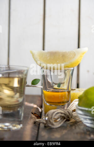 Scatti di tequila, limone calce e sale su uno sfondo di legno Foto Stock