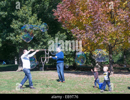 Fare gli uomini monster bolle di sapone con figli piccoli guardando in Prospect Park di Brooklyn, New York, Stati Uniti d'America Foto Stock