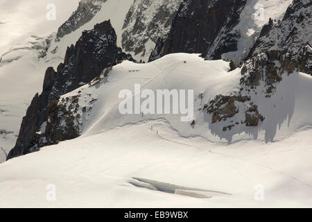 Mont Blanc du Tacul rivelato dalla nuvola di separazione dall'Aiguille du Midi, al di sopra di Chamonix, Francia, con gli alpinisti attraversando il Foto Stock