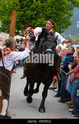 Un uomo è in consegna a un concorrente una ghirlanda di fiori, Kufenstechen, una tradizionale consuetudine e festival, Feistritz an der Gail Foto Stock