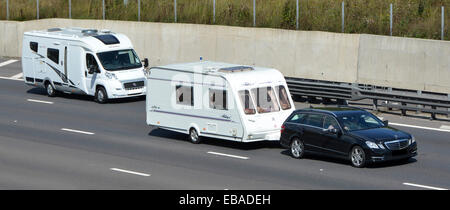 Due vacanze estive trasporto viaggio & campeggio opzioni auto trainante roulotte bianco sorpasso camper camper camper casa a motore guida lungo autostrada Inghilterra UK Foto Stock