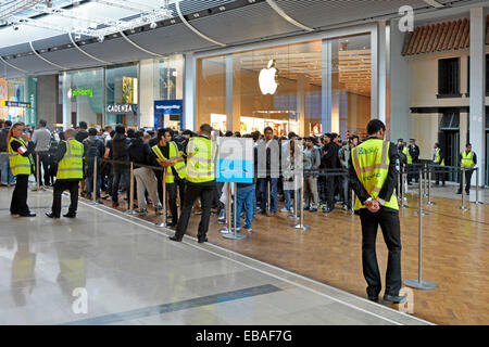 Il personale addetto alla sicurezza supervisiona folle di persone al di fuori del business Apple retail All'interno del negozio, il centro commerciale Westfield Stratford Newham East London Foto Stock