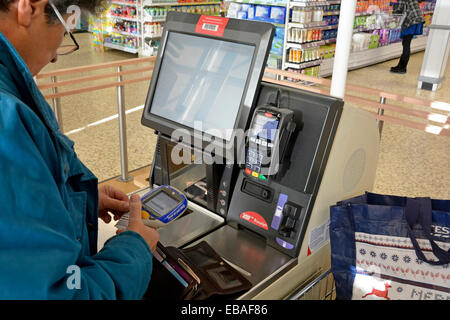 Donna e carrello al supermercato Tesco scansione self-service durante lo shopping e il download dei dati di acquisto sullo scanner portatile Londra Inghilterra Regno Unito Foto Stock