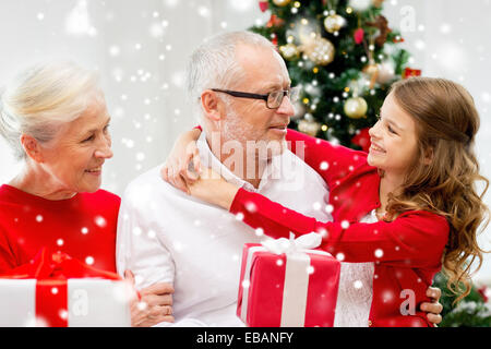 Famiglia sorridente con doni a casa Foto Stock