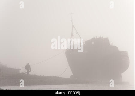 Loch Linnhe Scozia, Regno Unito. 28 Nov 2014. Una solitaria figura ammira la disastrata barca da pesca sulle sponde del Loch Linnhe durante una forte nebbia di mattina Credito: Kenny Ferguson/Alamy Live News Foto Stock