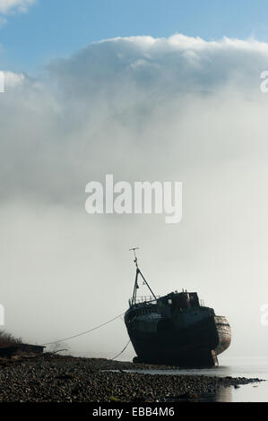 Distrutto la barca si trova sulle rive di Loch linnie come brume con il Ben Nevis in background Foto Stock