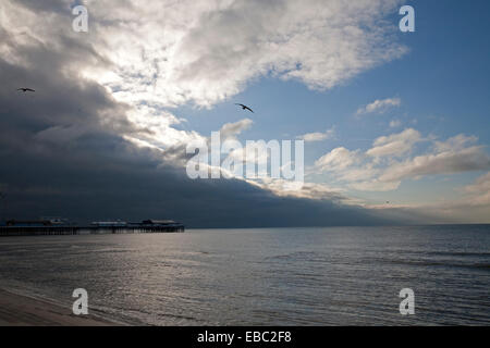 Nuvole temporalesche forma fuori in mare su Pier di Blackpool su un giorno inverni Foto Stock