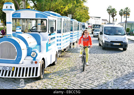 Il Portogallo, Algarve: treno turistico di Delgaturis, biker e auto passando il Jardim Manuel Bivar a Faro Foto Stock