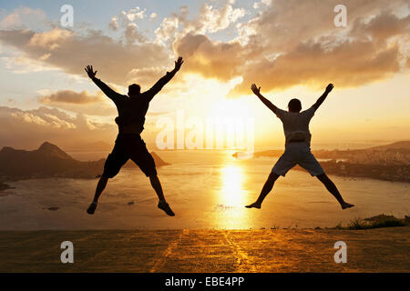 Gli adolescenti facendo salti di Star al tramonto con vista su Rio de Janeiro, Brasile Foto Stock