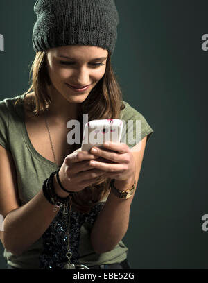 Ritratto di ragazza adolescente tramite telefono cellulare, Studio Shot Foto Stock