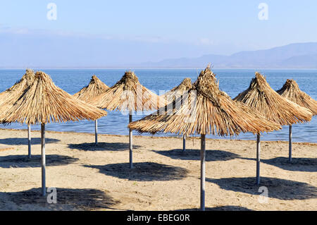 Ombre di reed ombrelloni su una spiaggia deserta Foto Stock