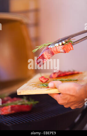 Uomo con le mani in mano closeup con bistecca di carne fresca preparazione sul grill Foto Stock