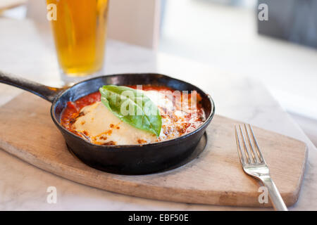 Lasagne al forno in una padella in ghisa con birra Foto Stock