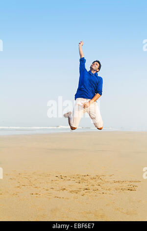 Uomo indiano lato mare Jumping Foto Stock