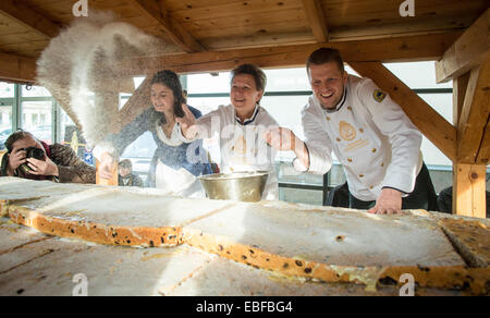 Dresden, Germania. 30 Novembre, 2014. Dresda di Lord Mayor Helma Orosz (2-R), Dresda Stollen ragazza Luise Fischer (L) e Baker Rene Krause (R) coprire il gigante lo Stollen con zucchero nella Neue Messe a Dresda (Germania), 30 novembre 2014. La torta gigante è composta da 40 pezzi stollen. Il gigante lo Stollen con taglio per il stollen Fest il 06 dicembre 2014. Foto: OLIVER KILLIG/dpa/Alamy Live News Foto Stock